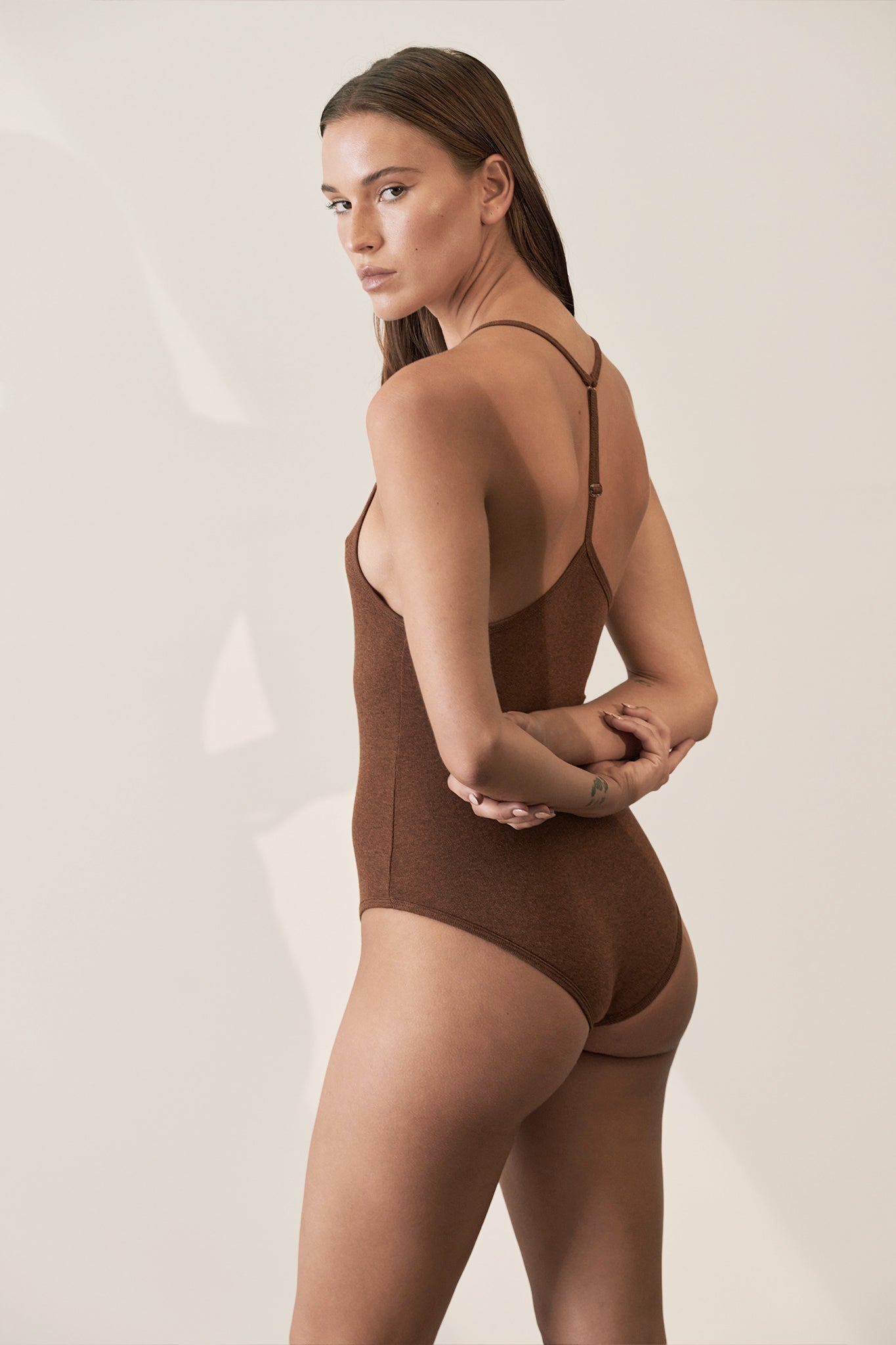 Brown ribbed bodysuit made from GOTS certified organic cotton, featuring a comfortable racerback design for versatile, everyday wear
