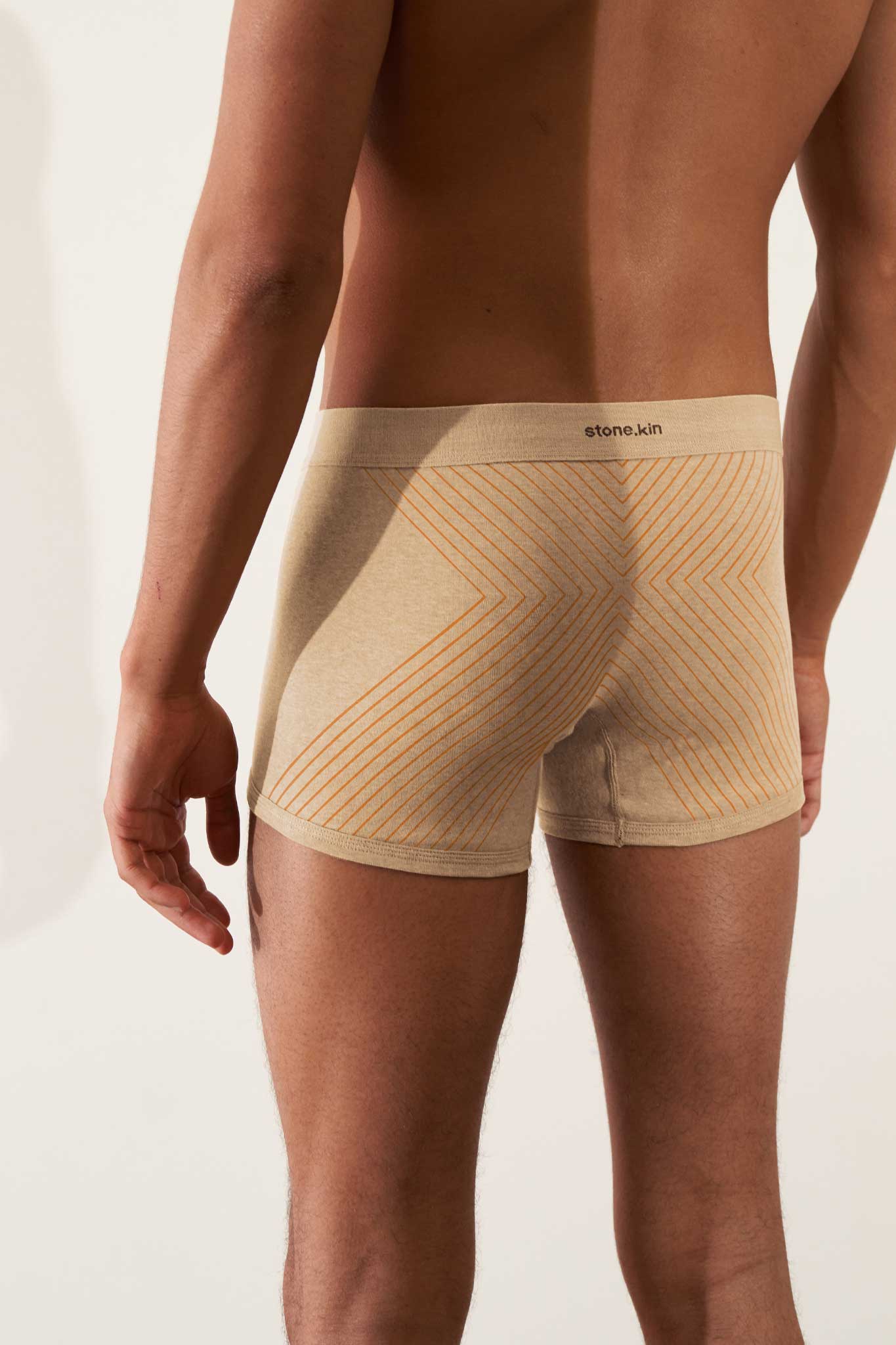 Boxer brief in organic cotton rib, sand melange with orange cross, showcasing comfort and GOTS certification.